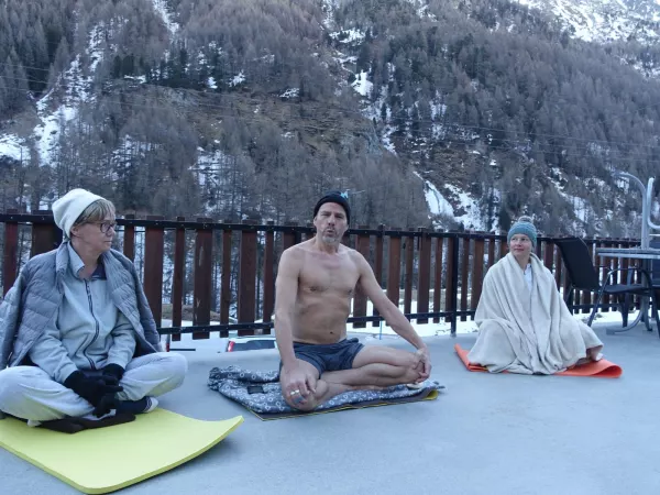 Méditation assise dans la neige sur une terrasse d'hôtel.